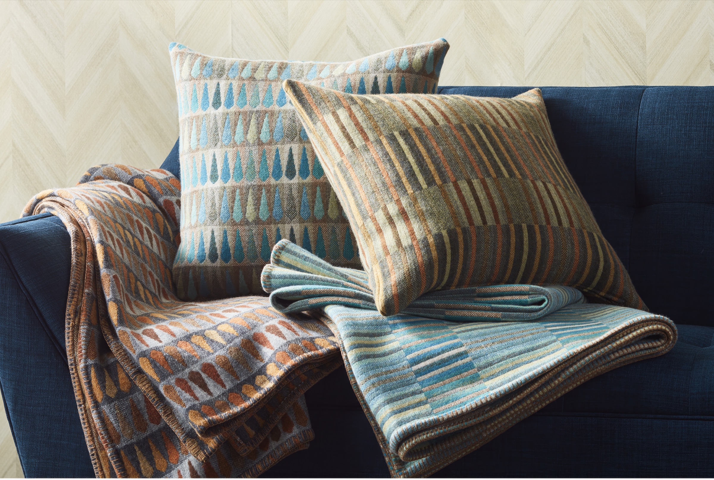Patterned blankets and pillows arranged on a deep blue sofa